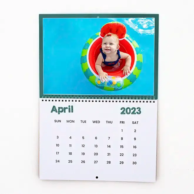 Personalised wall calendar for April 2023 featuring a colourful image of a smiling child in a pool float. The calendar has a clean, minimalist design with dates clearly marked. Ideal for gifts such as baby shower gift ideas, Christmas gifts, or personalised gifts in South Africa.
