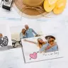 Personalised photo book featuring a couple on the cover with the text ''This is our story'' and a pink heart graphic. Ideal for gifts for men, baby shower gift ideas, Christmas gifts, and Valentine''s Day gift ideas. Displayed on a white wooden surface with a straw hat, yellow flip-flops, and a camera.